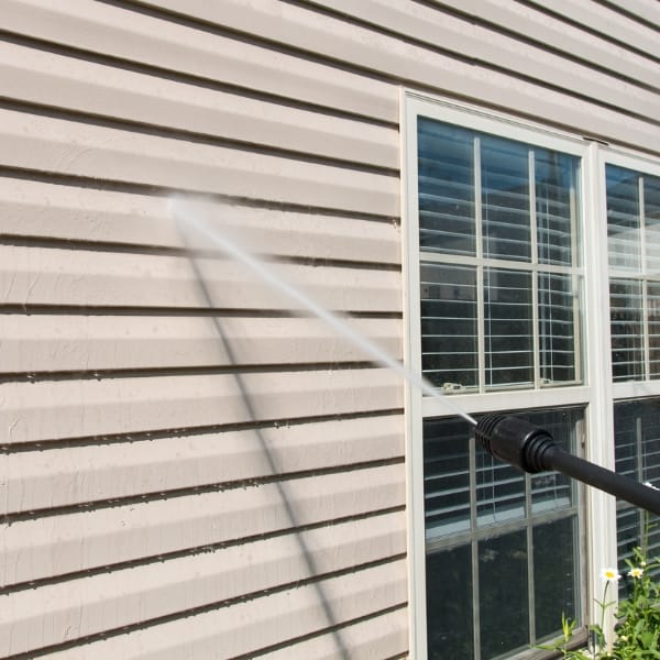 Power washing services are expertly applied to the siding of a house, especially near windows, ensuring all areas are pristinely clean.