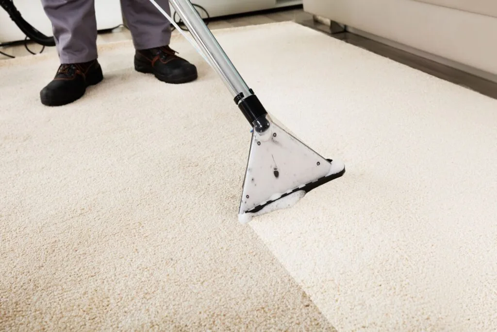 A person skillfully operates a professional carpet cleaning machine, restoring the pristine look of a beige carpet.