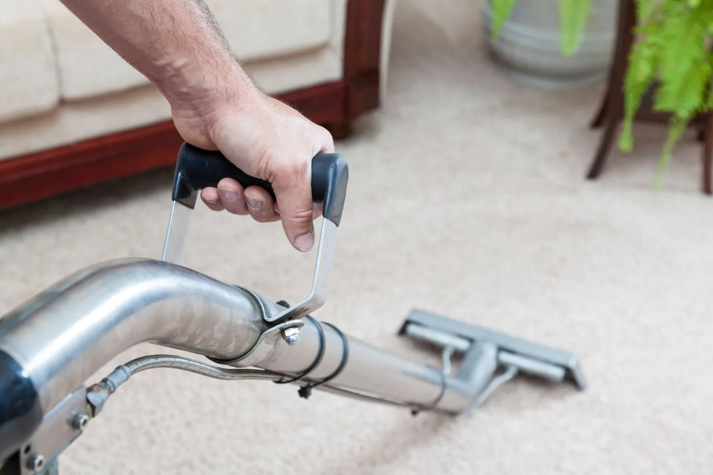 A person is expertly maneuvering a cleaning machine over the plush beige carpet, restoring its original luster.