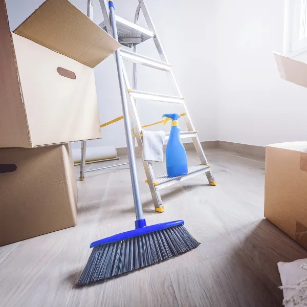 The room is cluttered with cardboard boxes, a broom, a spray bottle, and a ladder. It's one of those areas that could benefit from some organization services to create a tidier space.